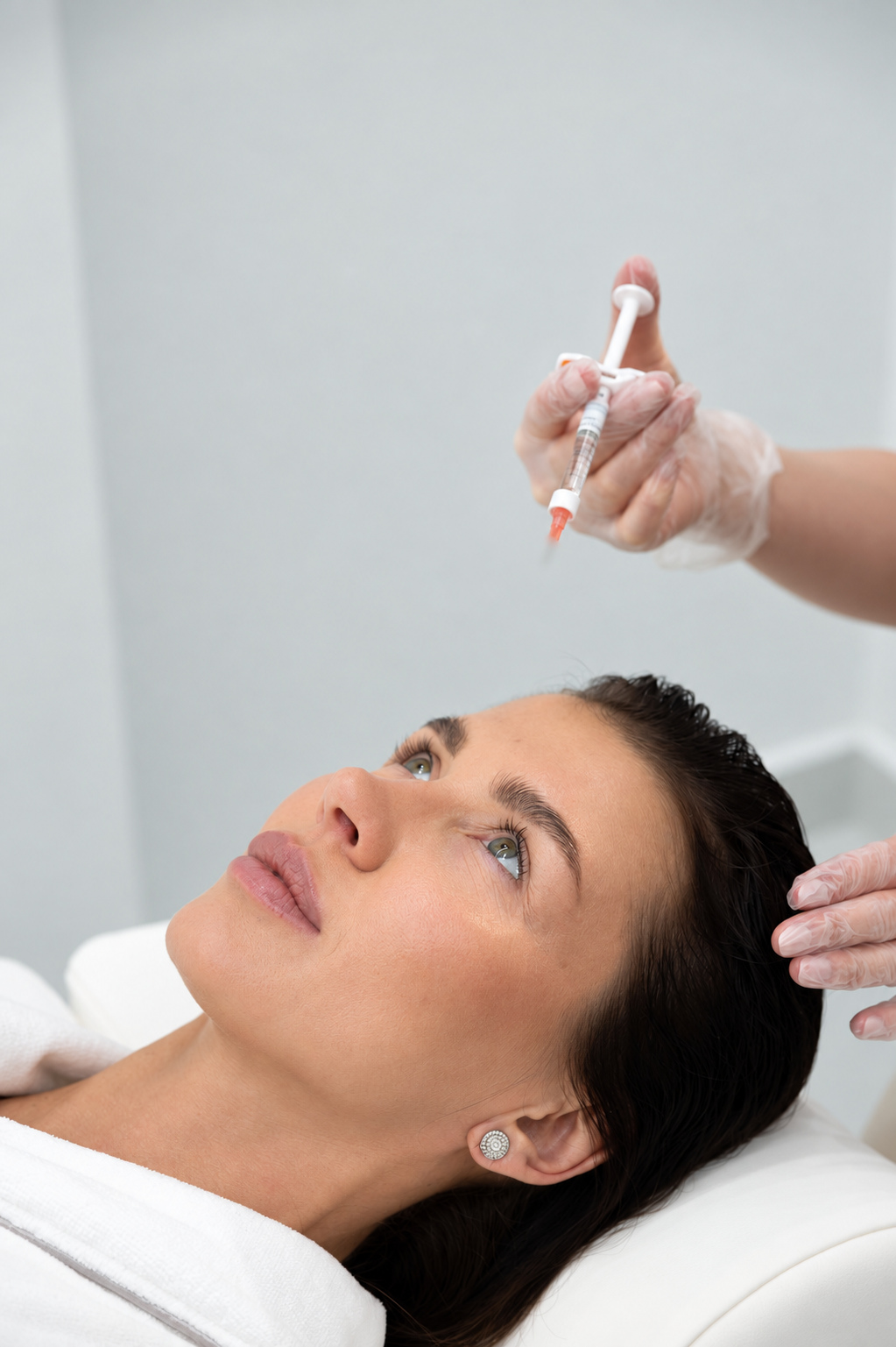 Patient reclining while a practitioner holds a syringe with the needle blurred