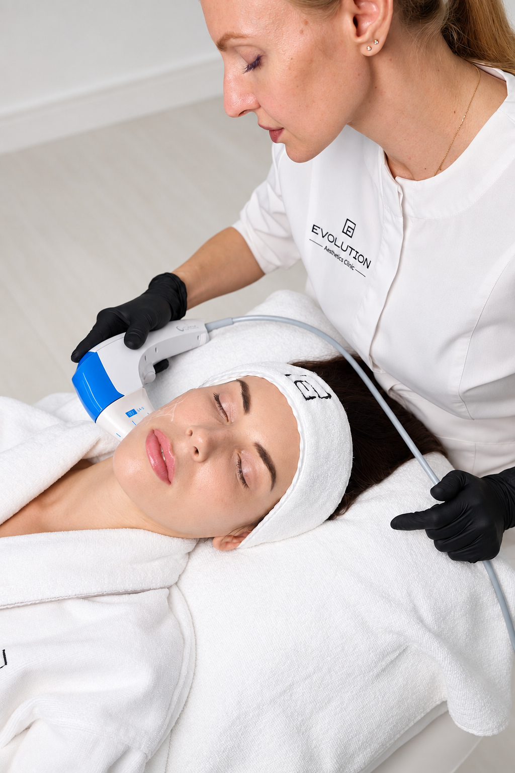Practitioner using a blue Ultraformer MPT handpiece on a patient cheek