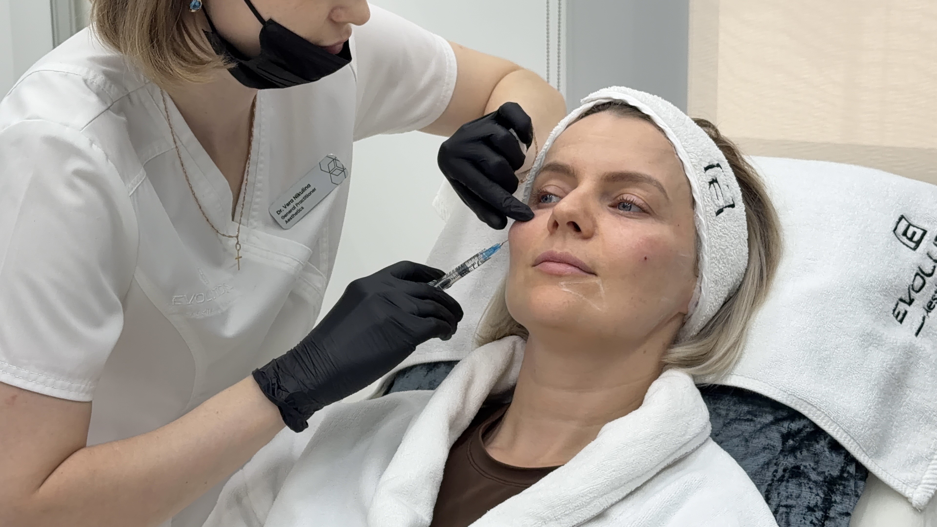 Clean landscape treatment shot of the cheek zone Sculptra addresses; badge and uniform give clinic authenticity