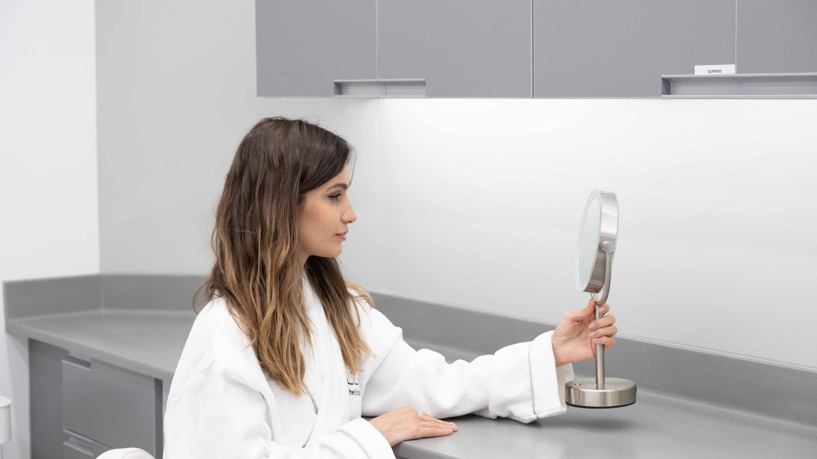 Woman using a hand mirror in a clinic consultation room